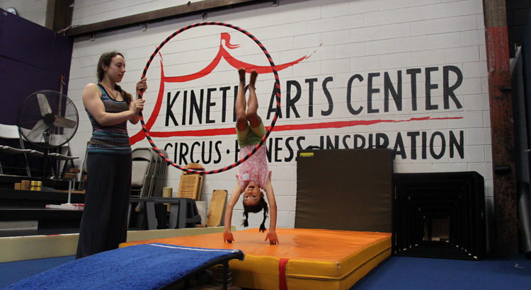 Coach holds a hula hoop, kid dives through